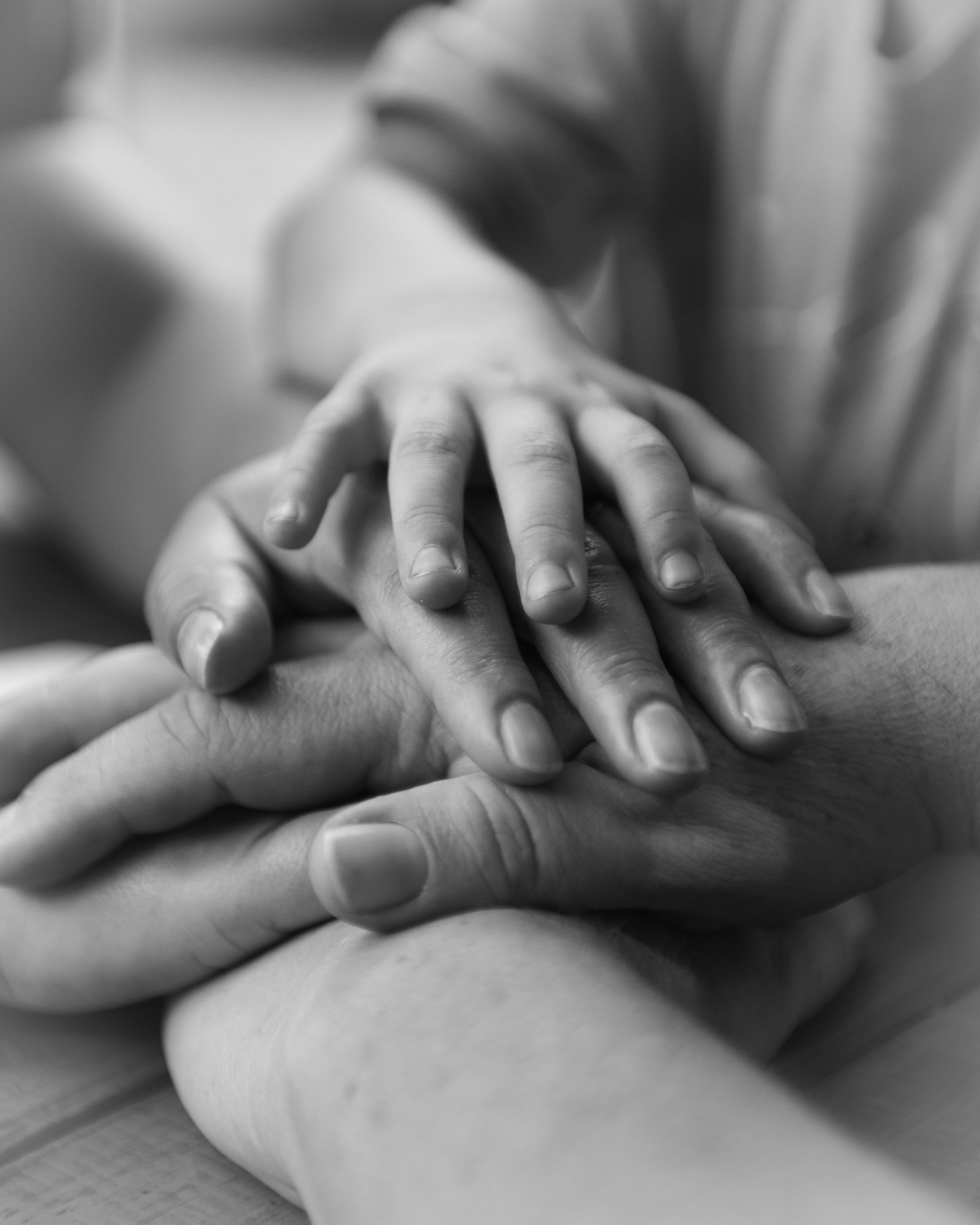 Close-up of multiple hands, including a child's hand, resting together in a caring gesture.